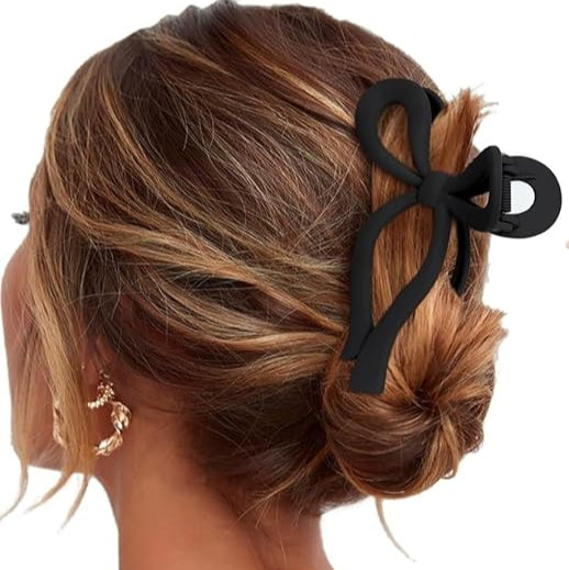 Woman with styled hair featuring a black bow accessory on a white background