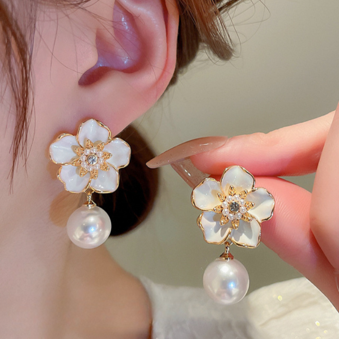 Floral earrings with pearl drops worn by a person