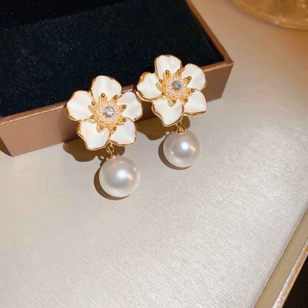 Floral earrings with pearl drops on a textured surface