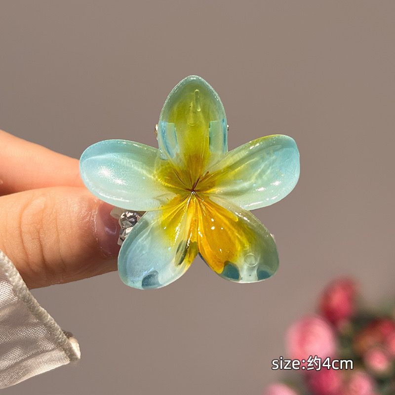 Transparent flower-shaped hair clip held by a hand with a blurred background