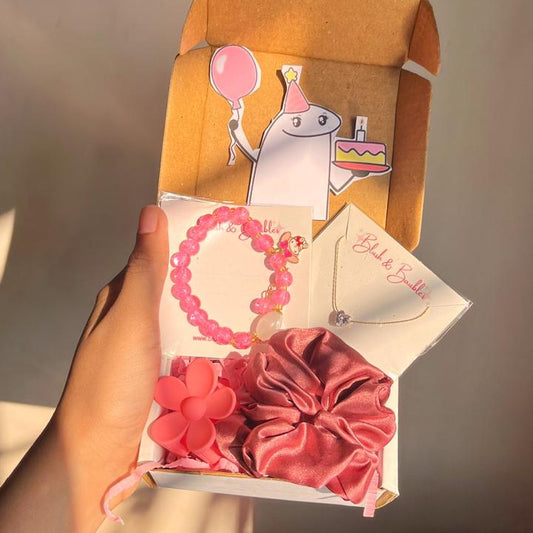 Hand holding a box with pink hair accessories and a card on a plain background