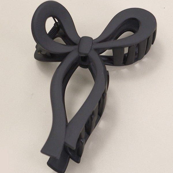Black bow-shaped hair clip on a beige background