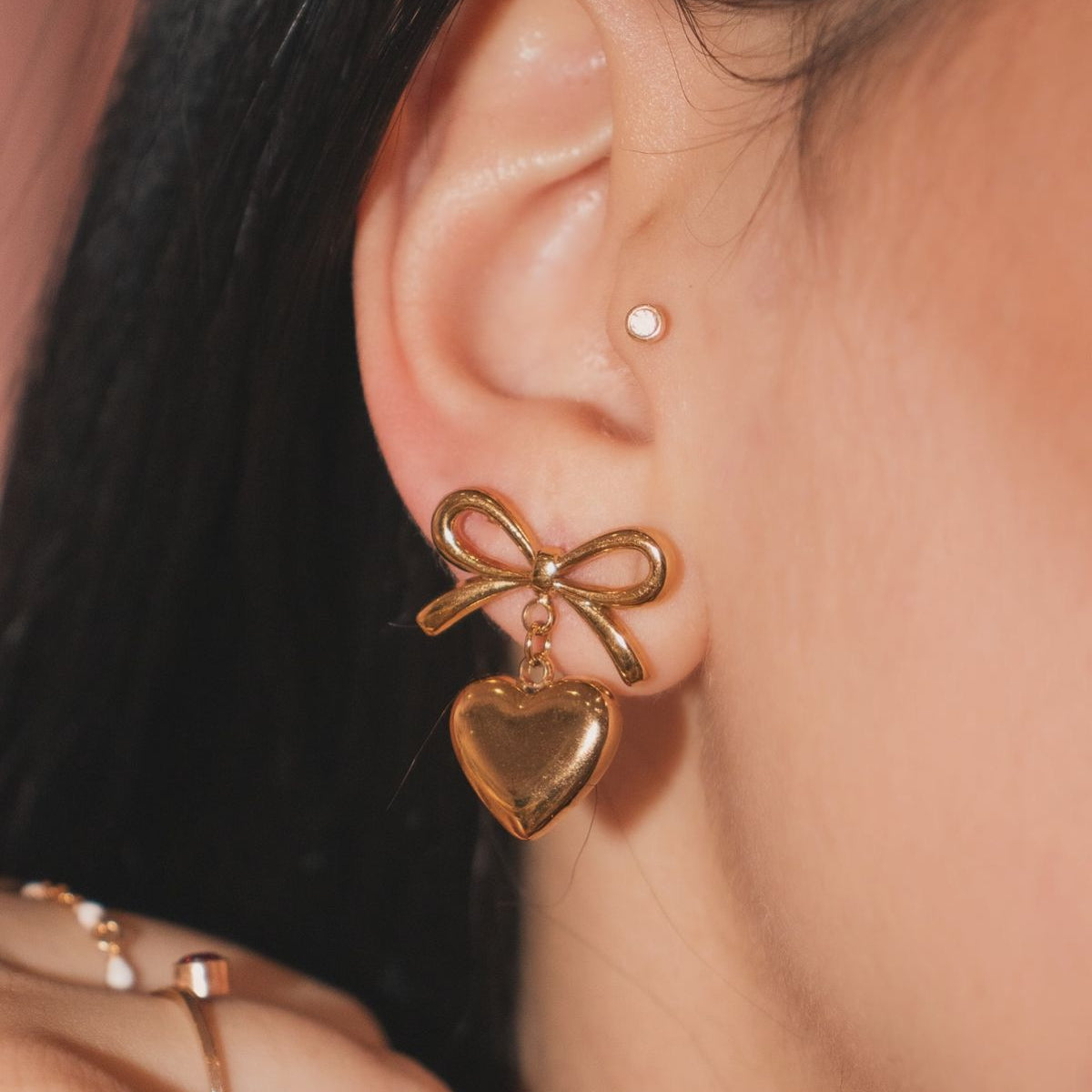 Gold bow-shaped earring worn by a person