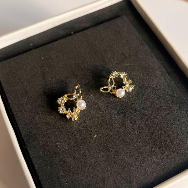 Pair of gold earrings with pearls in a box on a light surface