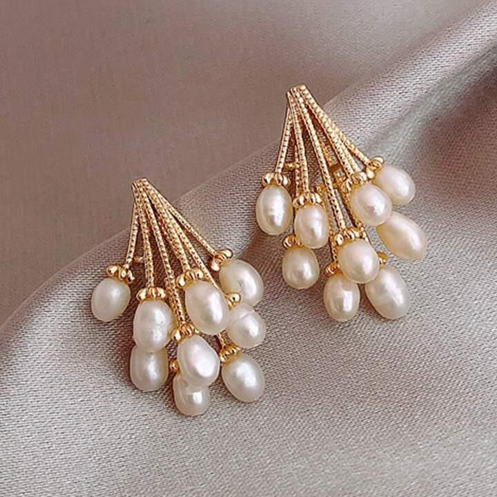 Pair of pearl earrings with gold accents on a soft fabric background