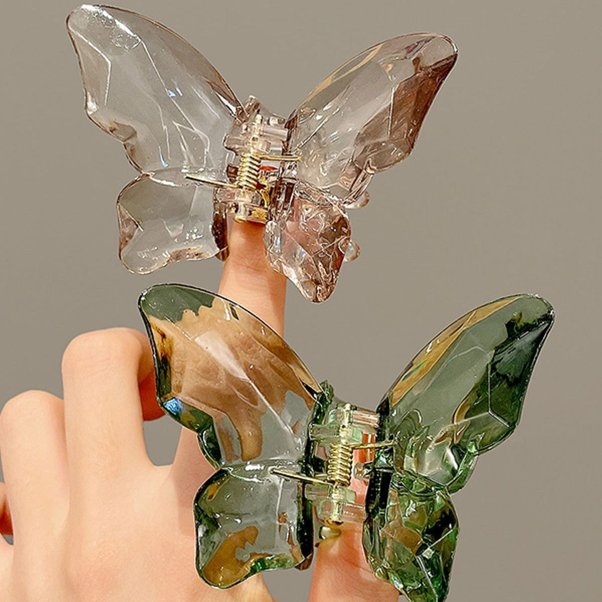 Clear and green butterfly-shaped earrings on a neutral background