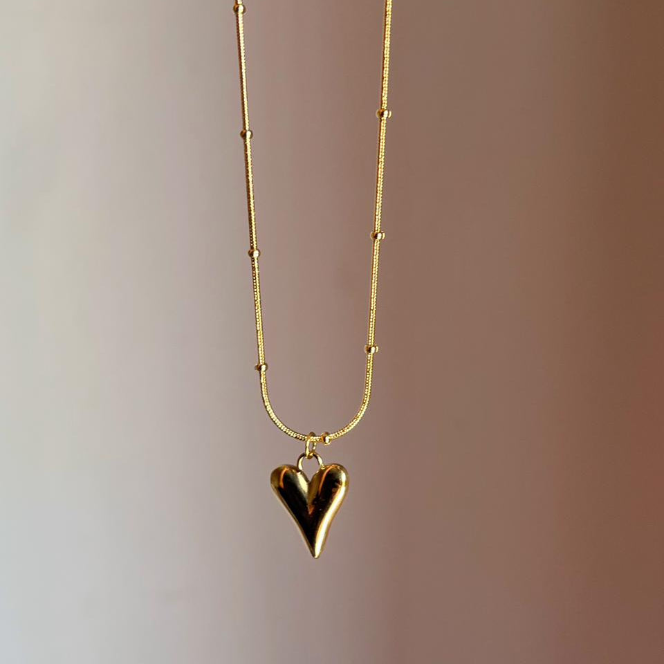 Gold heart-shaped pendant necklace on a gradient background