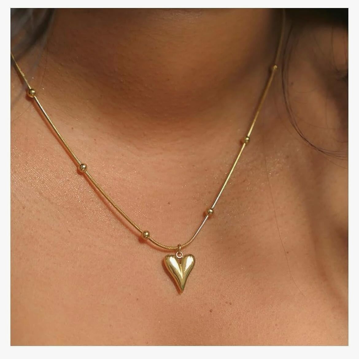 Gold necklace with a heart pendant on a person's neck