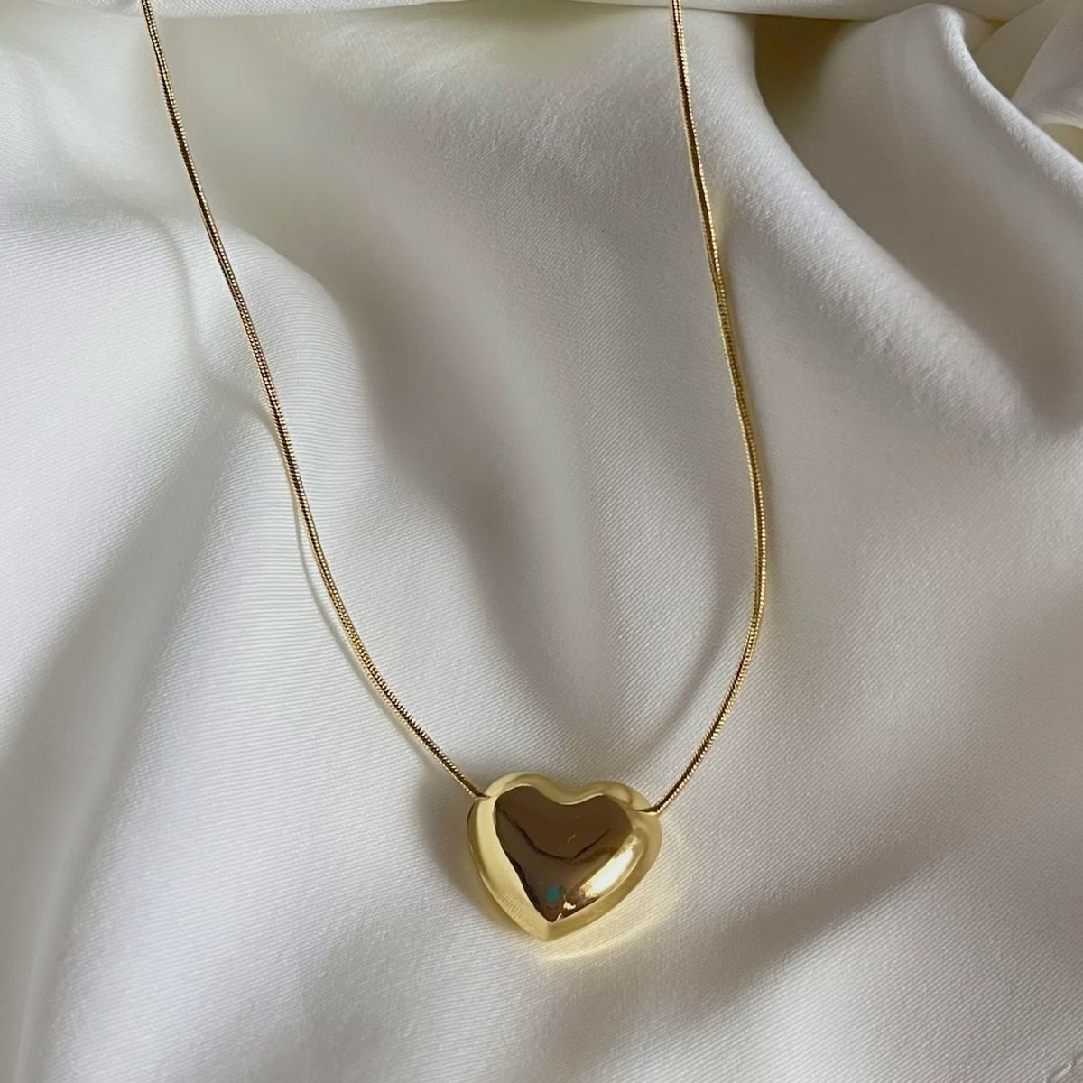 Gold heart-shaped necklace on a white fabric background