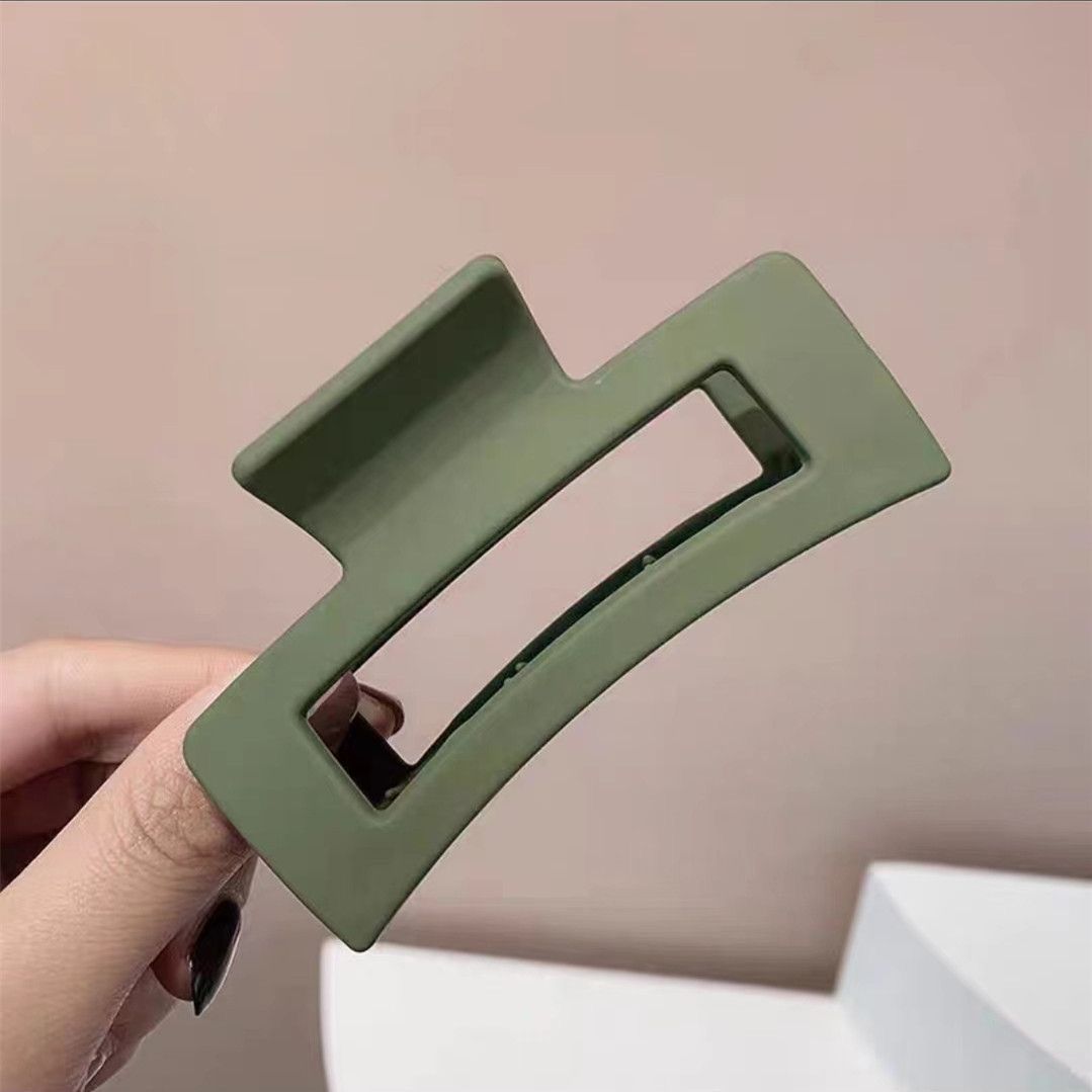 Green rectangular hair clip held by a hand against a plain background