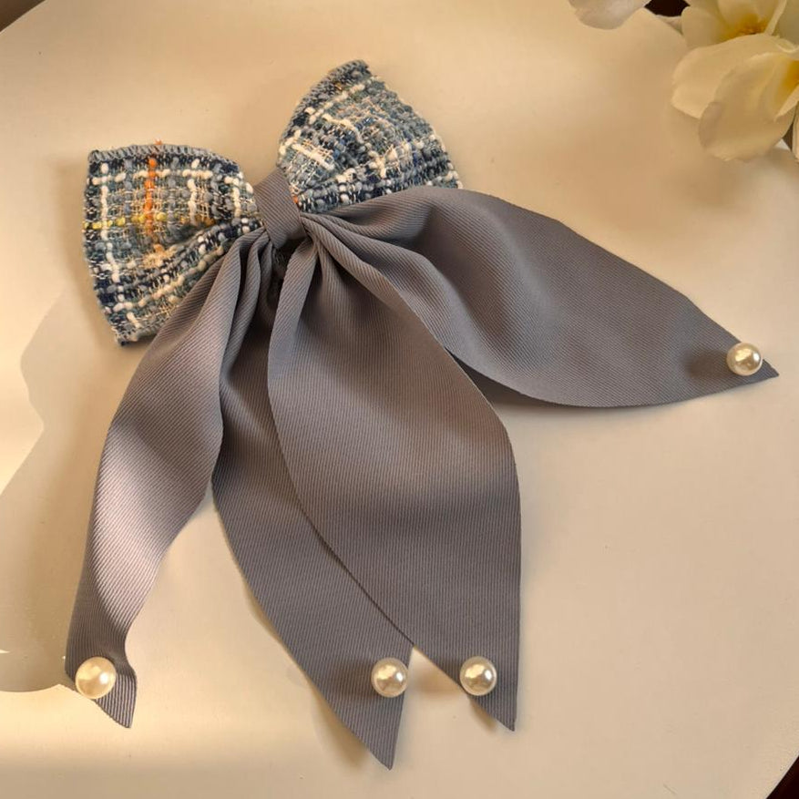 Gray bow with decorative elements on a white surface with flowers in the background