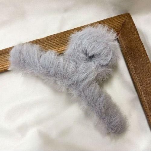 Gray fluffy Hair Clip on a wooden frame against a white background