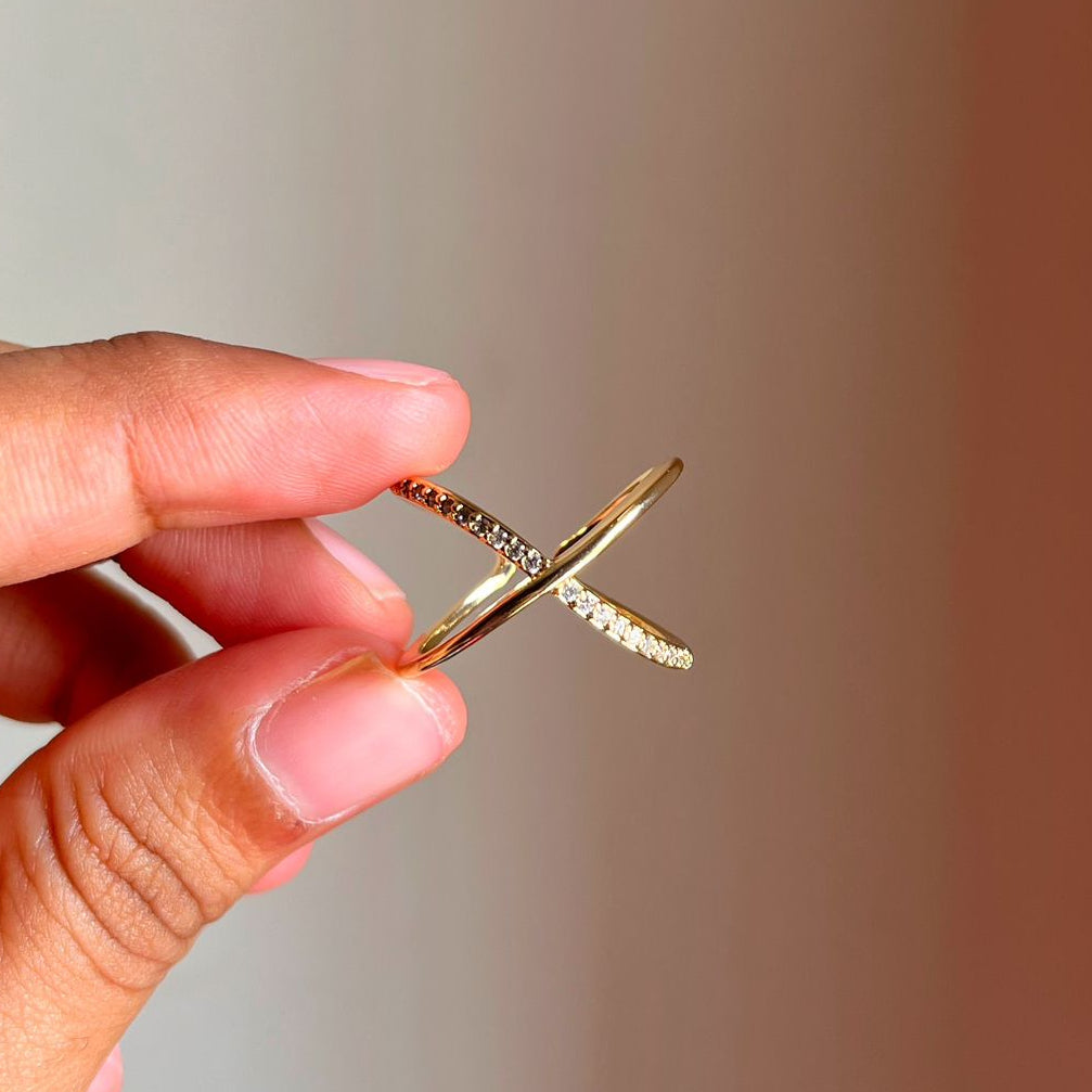 Gold Infinity Ring held by a hand against a gradient background