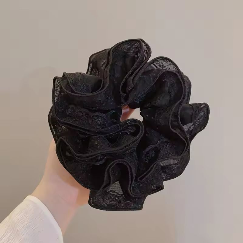Black lace scrunchie held against a plain background