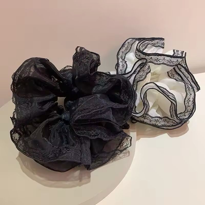 Black lace scrunchie and white lace bralette on a beige background