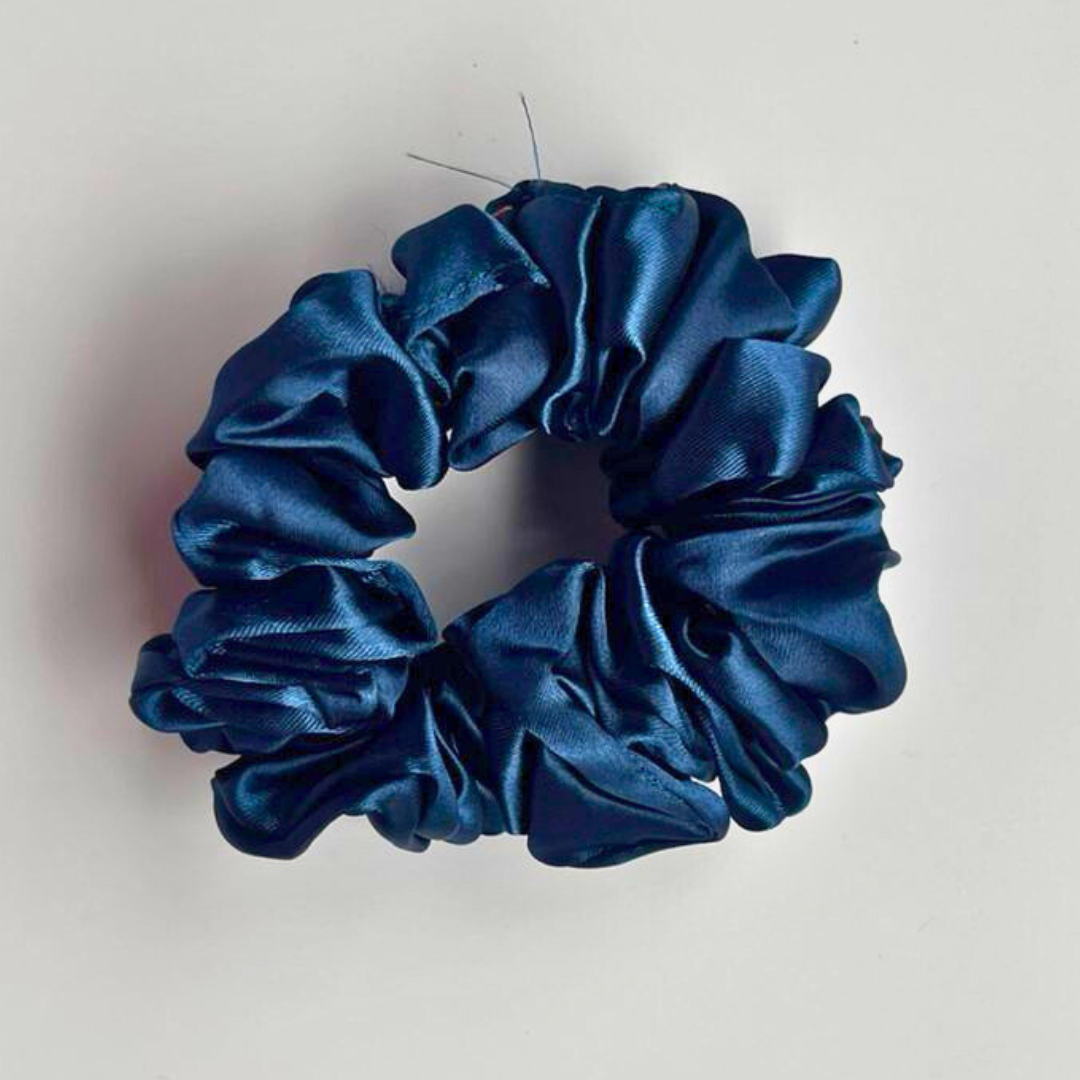 Blue satin scrunchie on a light gray background