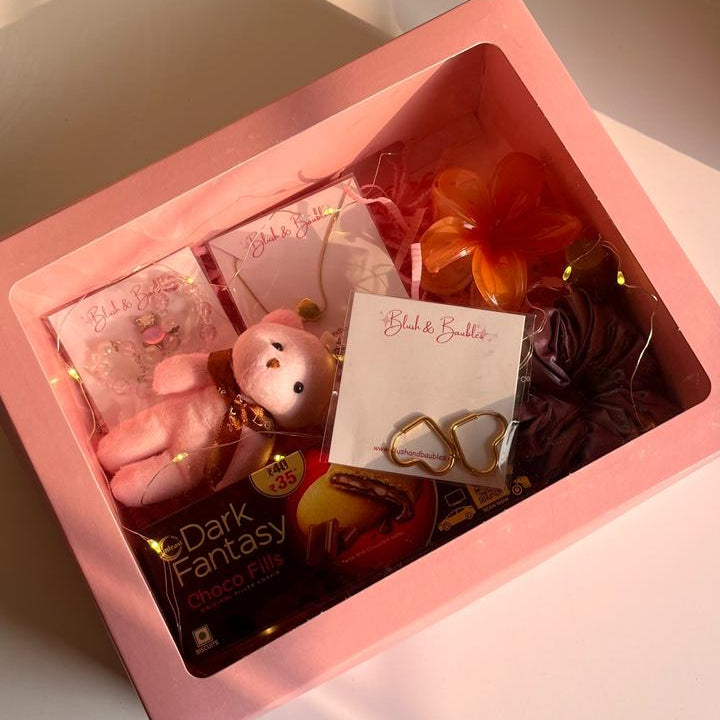 Pink gift box with 'Dark Fantasy' chocolate and decorative items on a light surface