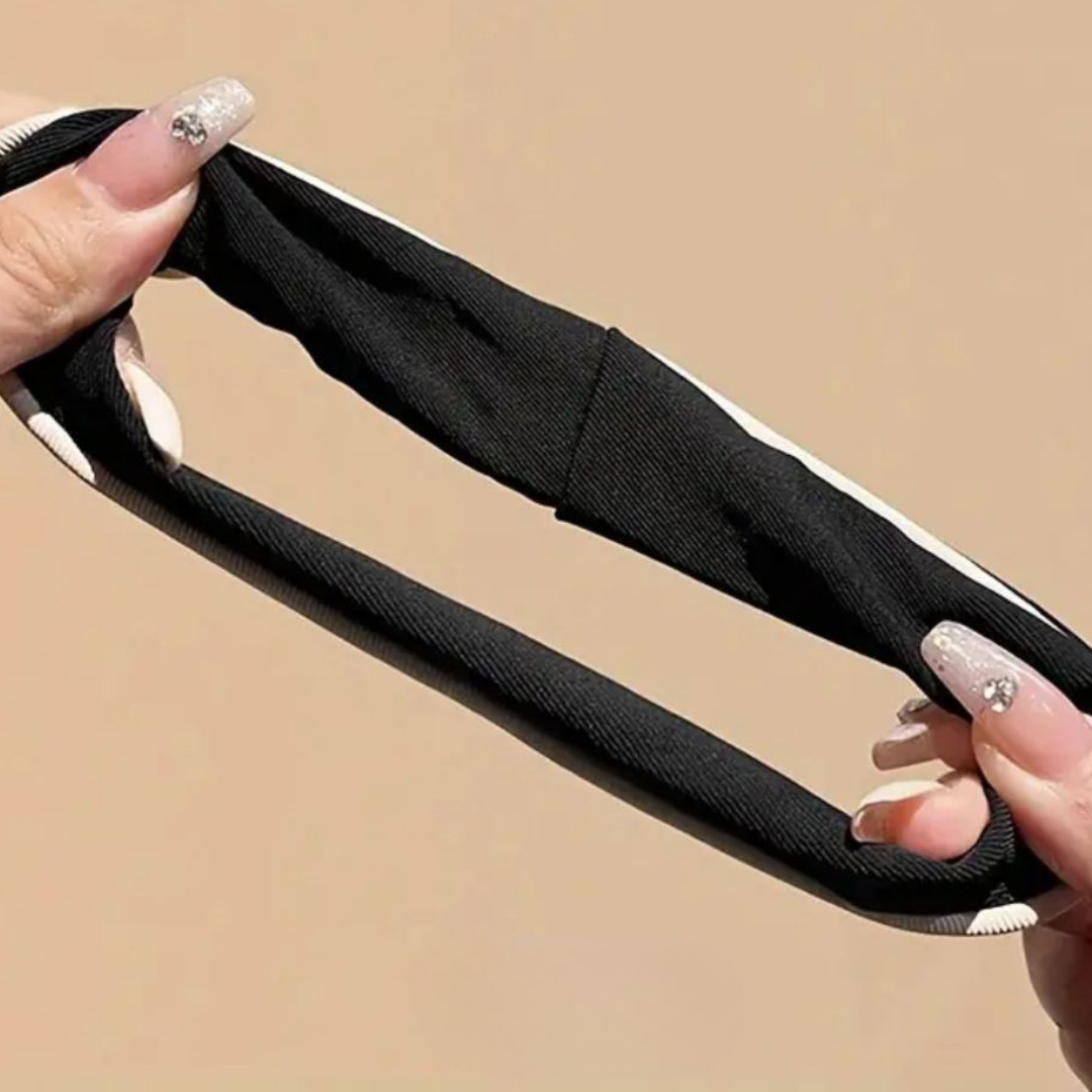 Black headband held by hands against a beige background