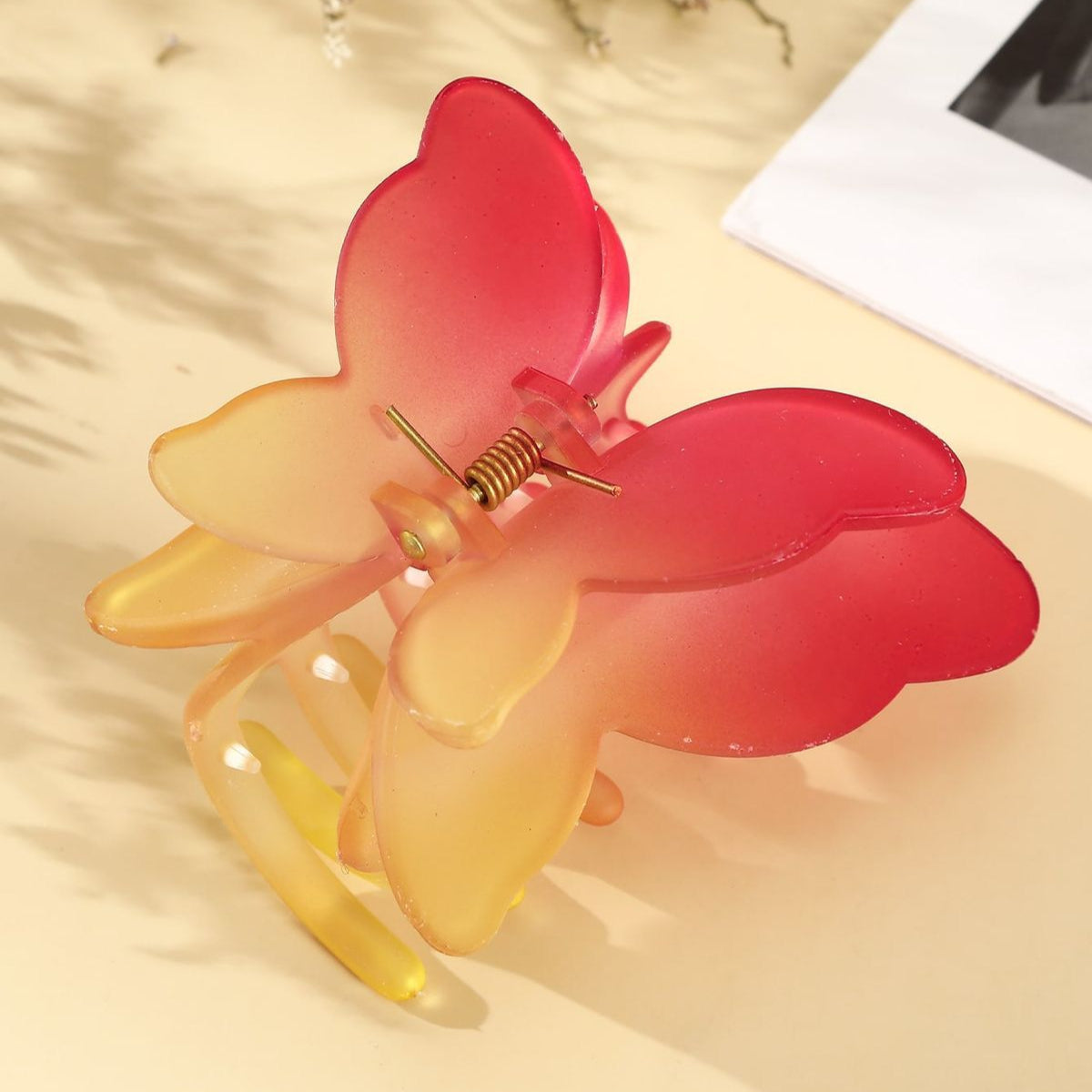 Butterfly-shaped hair clip with red and yellow colors on a light background