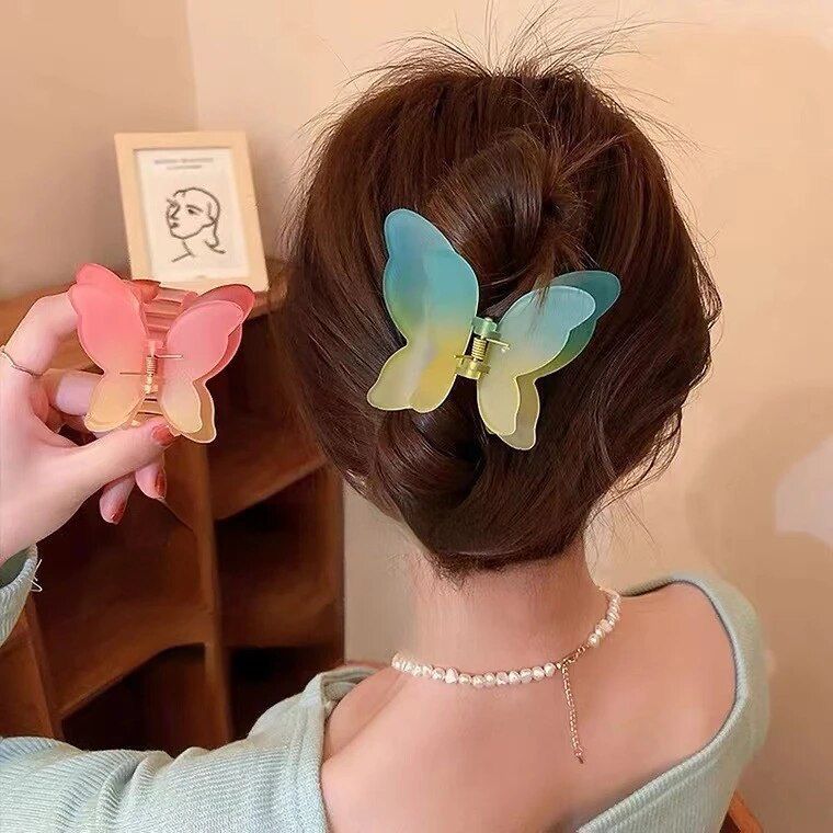 Person with butterfly-shaped hair clips in their hair, holding a pink clip.