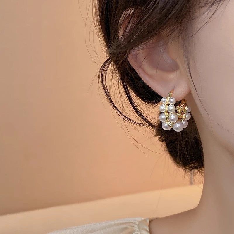 Pearl hoop earring worn by a person with a soft beige background