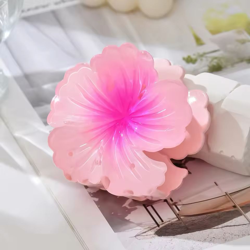 Pink flower-shaped hair clip on a textured surface