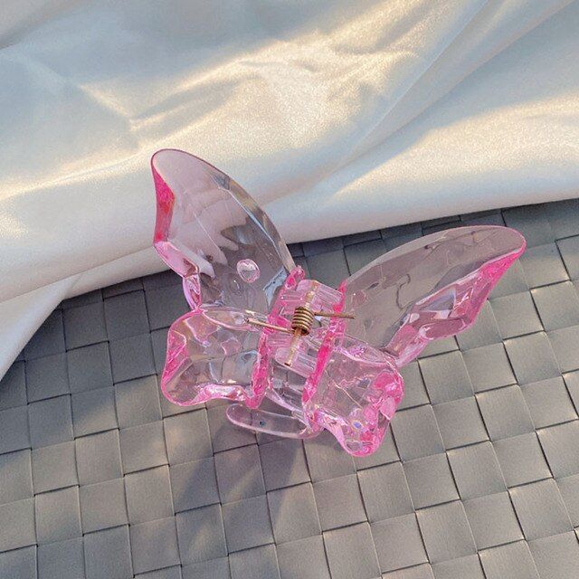 Pink butterfly-shaped hair clip on a textured surface