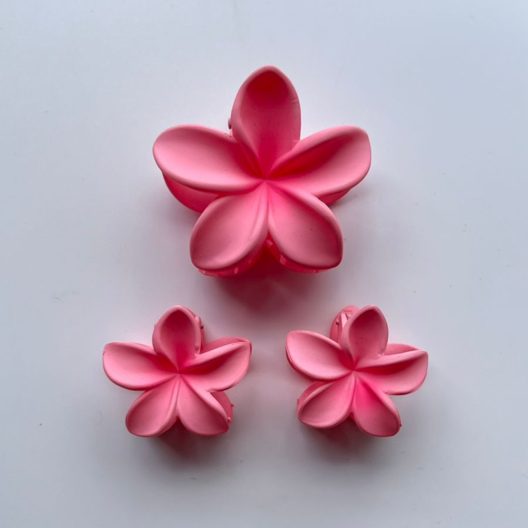 Three pink flower-shaped claw clips on a white background.