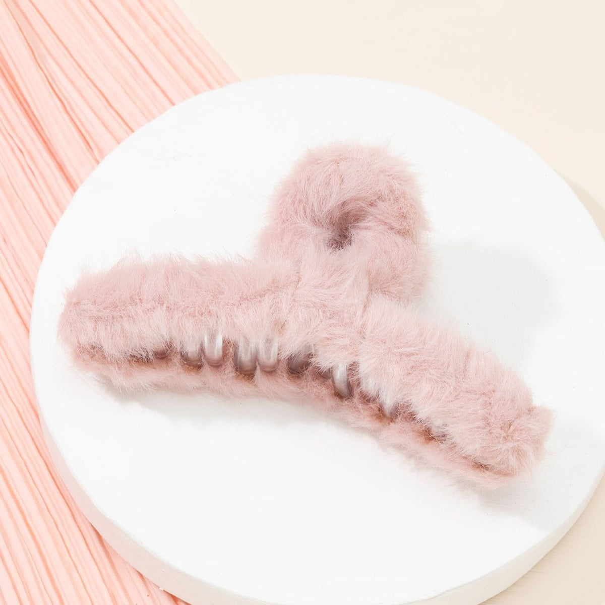 Fur Hair Clip on a white plate with a soft pink background