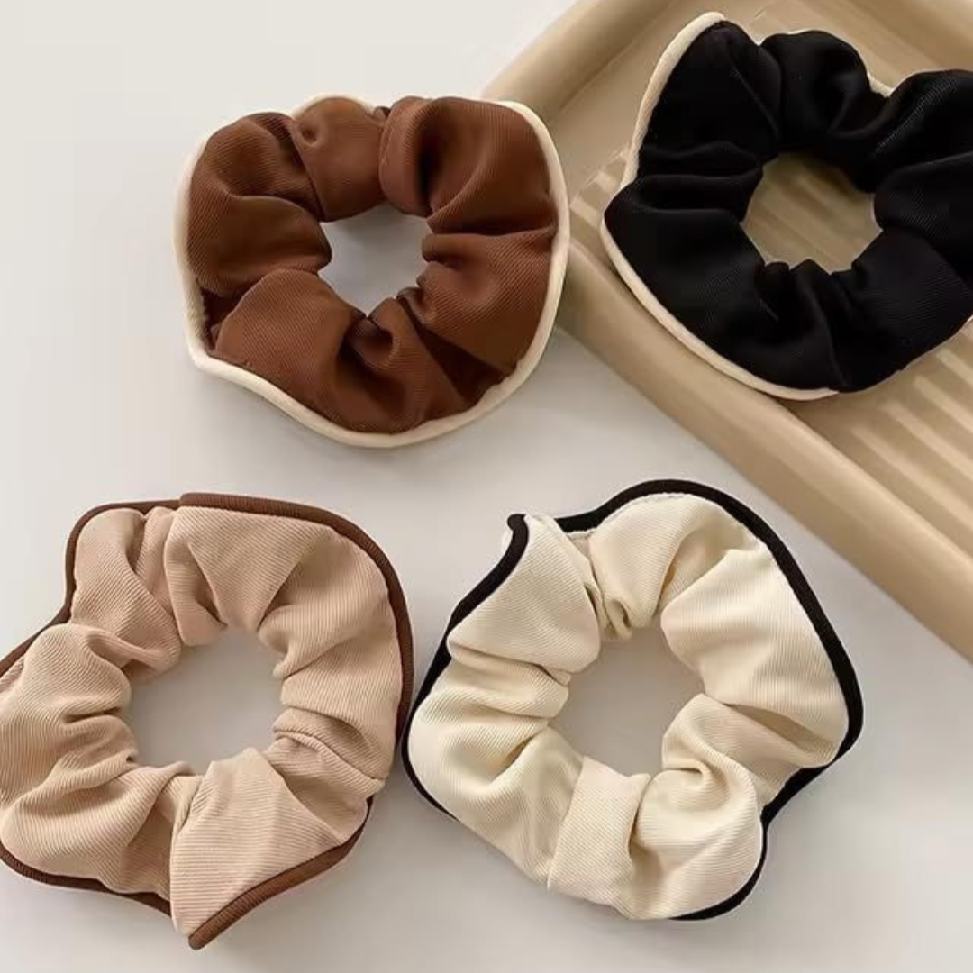 Four scrunchies in brown, beige, black, and cream on a white background.