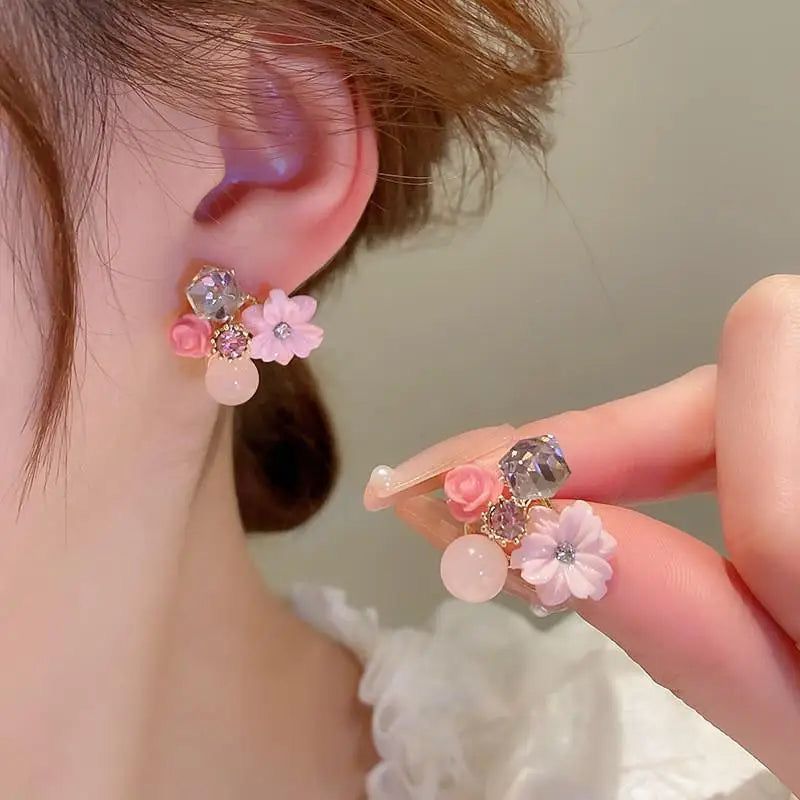 Close-up of a person wearing floral earrings with a neutral background