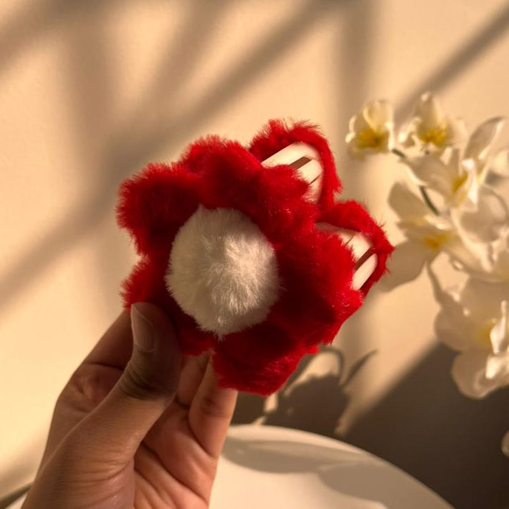 Red and white hair clip held by a hand with a blurred background