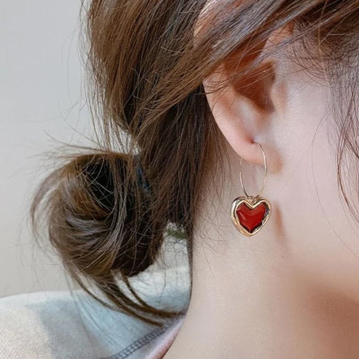 Heart-shaped earring worn by a person with a blurred background