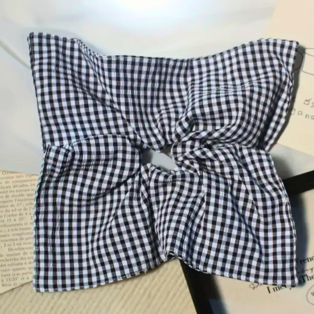 Black and white checkered fabric with a bow on a textured surface