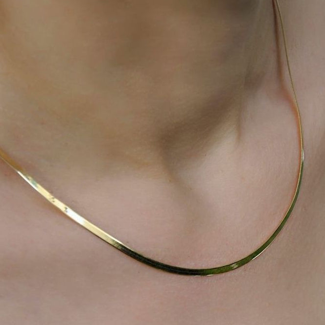Gold Snake Chain necklace on a person's neck with a neutral background