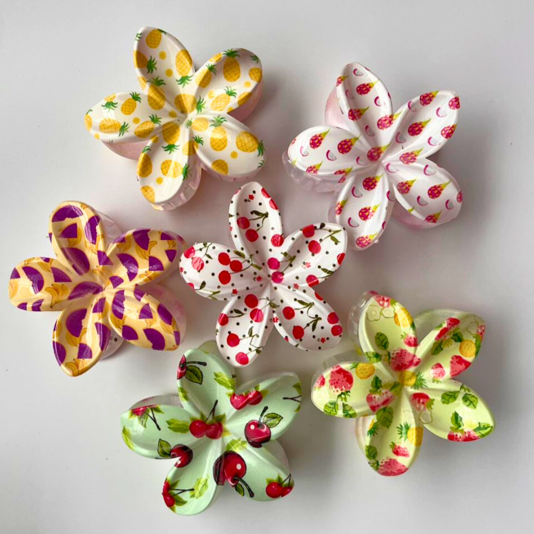 Set of colorful flower-shaped hair clips on a light gray background