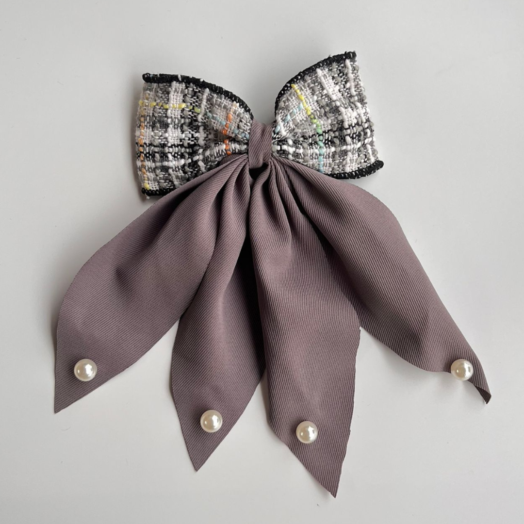 Bow-shaped hair accessory with tweed top and gray ribbon on a light gray background