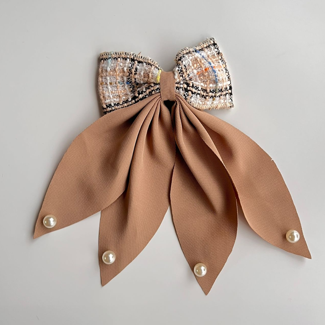 Decorative bow with sequined top and brown ribbon on a gray background