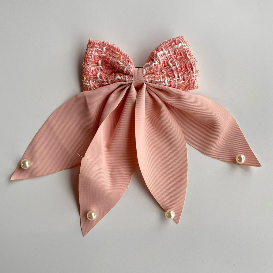 Pink bow hair clip with a textured center on a gray background
