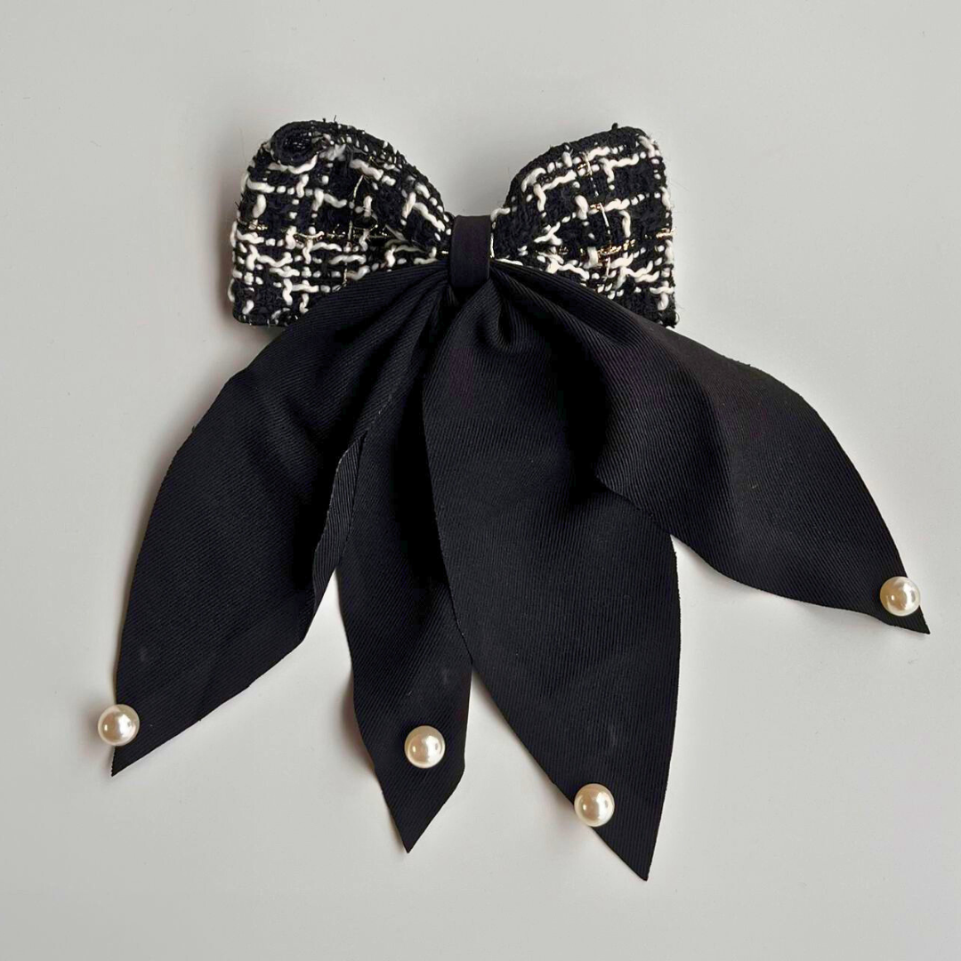 Black bow with pearl accents on a gray background