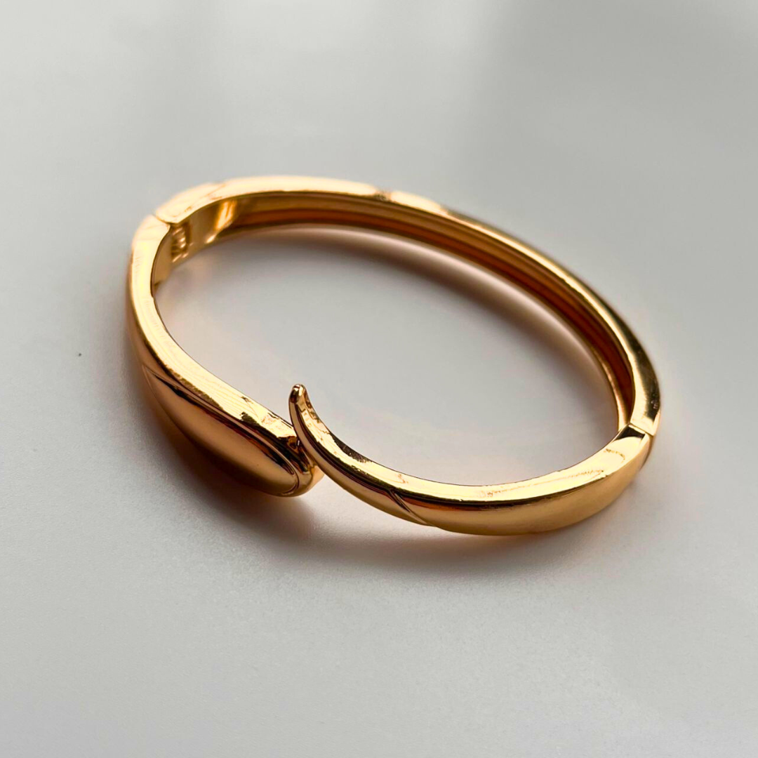 Gold bracelet on a light gray background