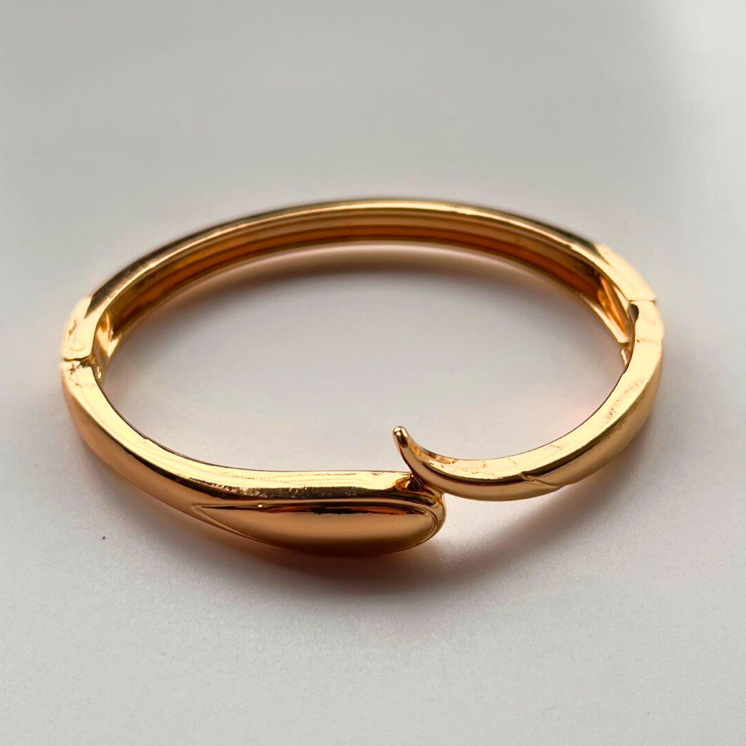 Gold bracelet with a unique design on a light gray background
