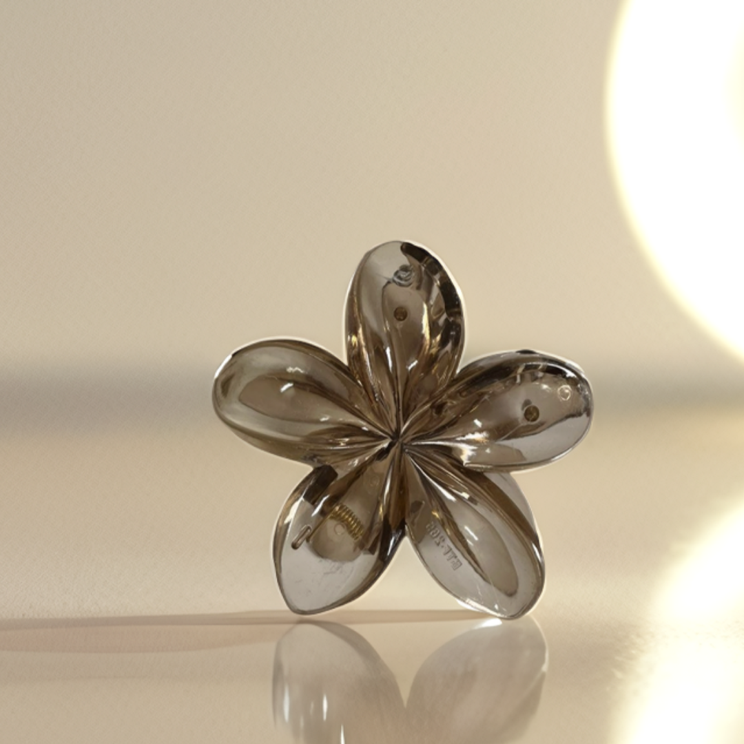 Silver flower-shaped object on a reflective surface with a light background