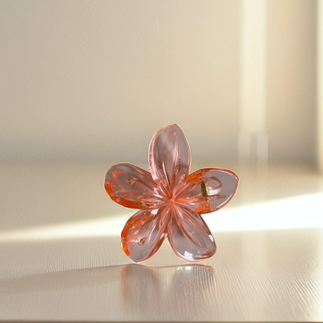 Translucent pink flower-shaped object on a reflective surface with a blurred background