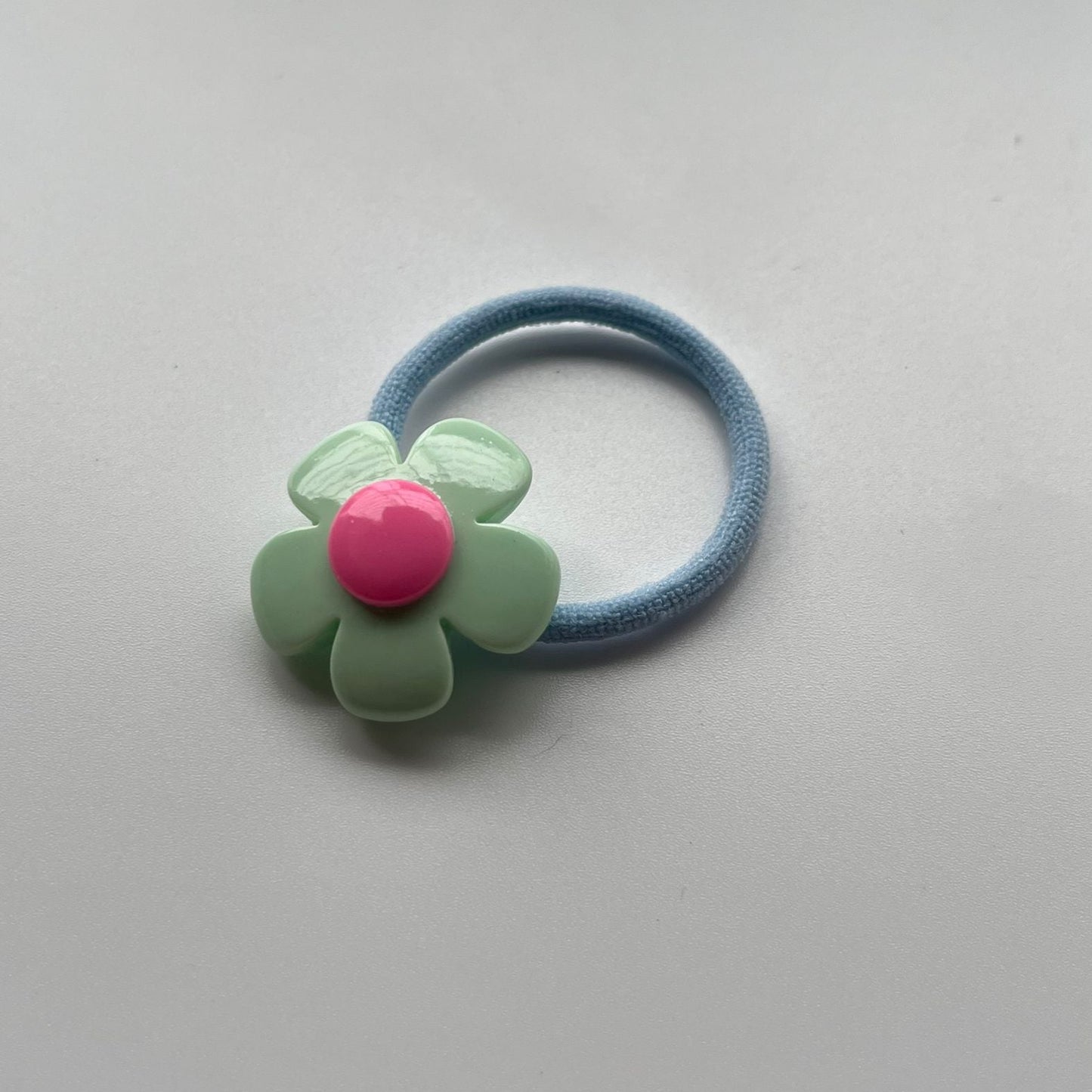 Hair elastic with a flower-shaped holder on a light gray background