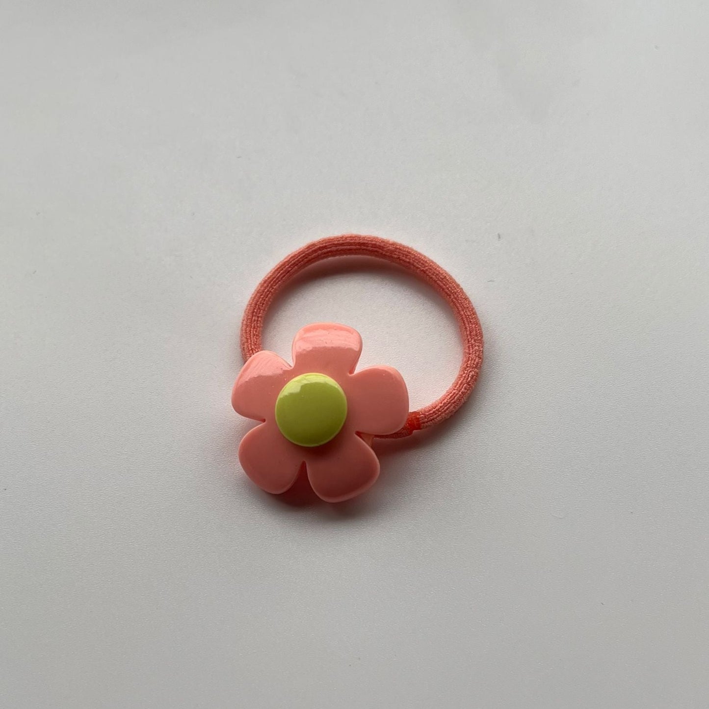 Pink flower-shaped hair tie on a white background