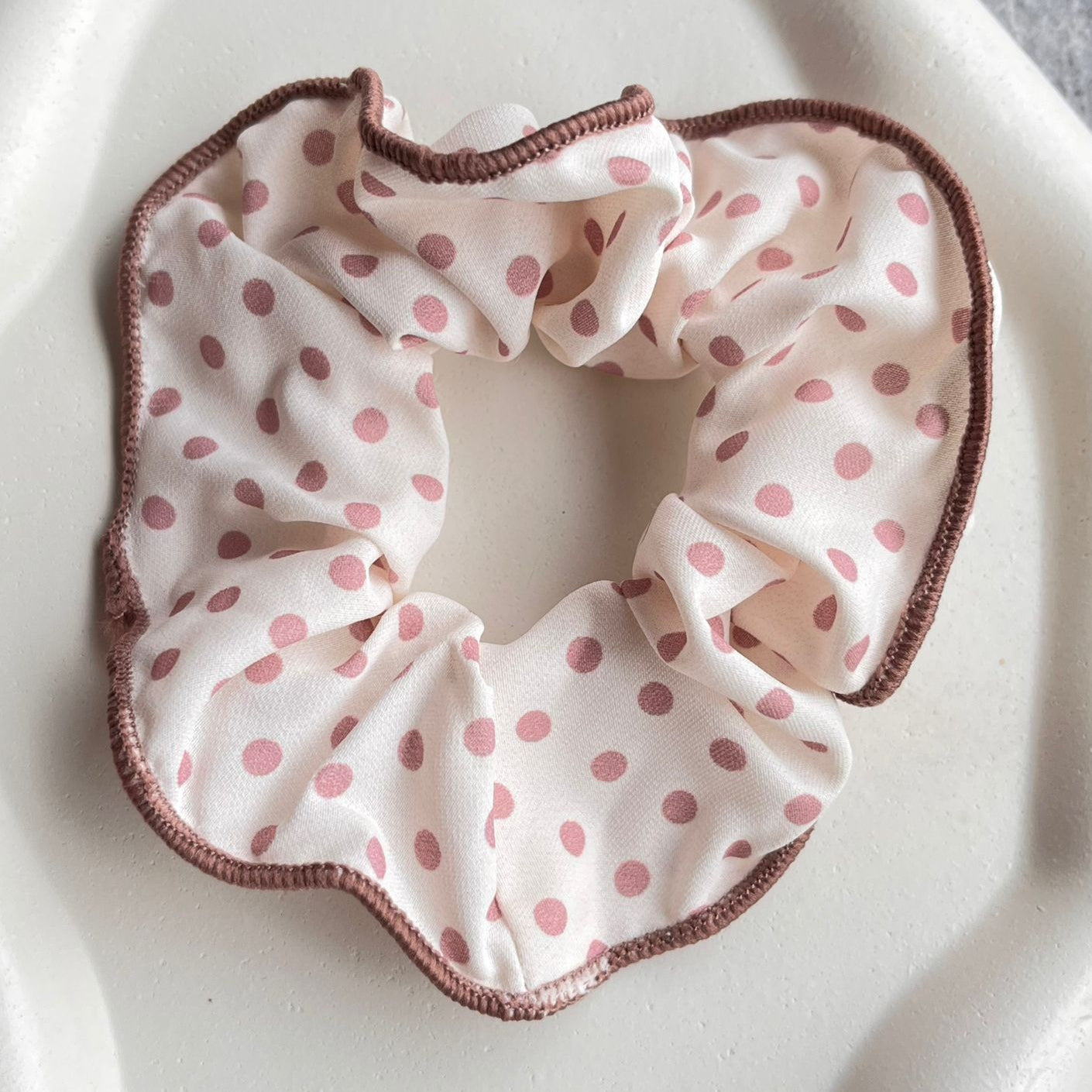 Pink polka dot scrunchie on a white surface