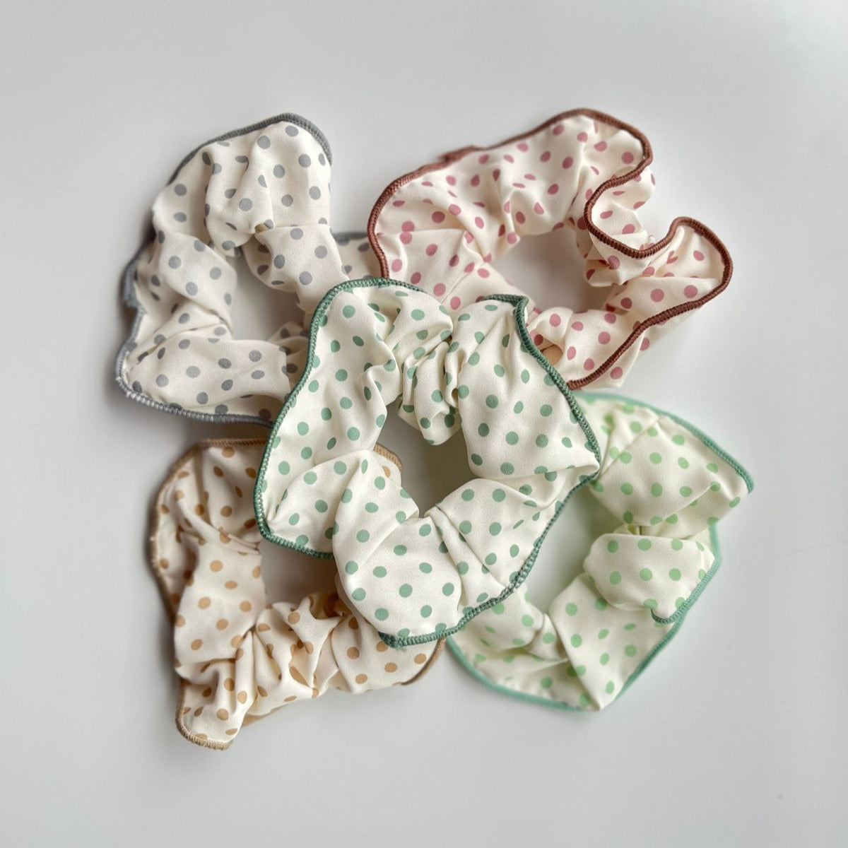 Set of four polka dot scrunchies on a light gray background