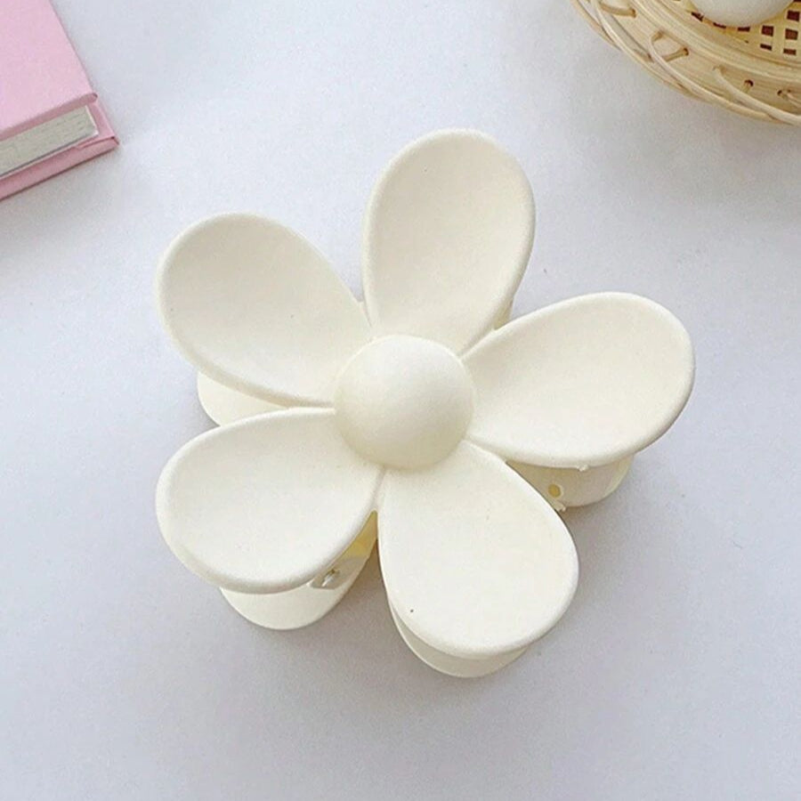 White flower-shaped claw clip on a light grey background
