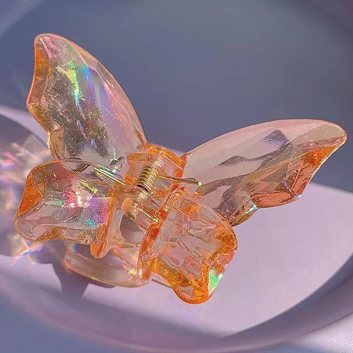 Butterfly-shaped hair clip with iridescent wings on a reflective surface